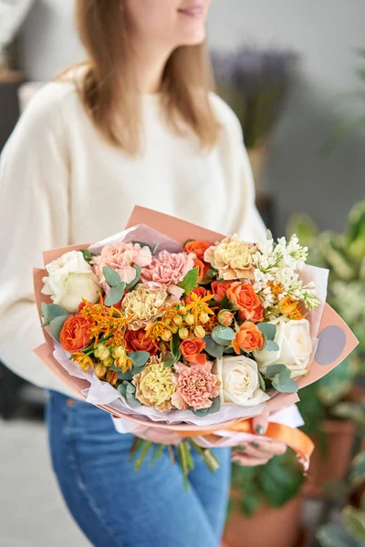 Tienda floral europea. Hermoso ramo de flores mixtas en manos de mujeres. el trabajo de la floristería en una florería. Entrega flor fresca cortada . — Foto de Stock