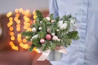Noel havası. Metal bir tencerede taze ladin aranjmanı. Arka planda çelenk ışıkları Bokeh.