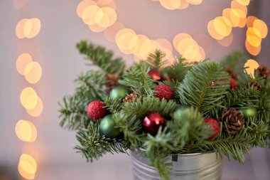 Metal bir tencerede taze ladin aranjmanı. Noel havası. Arka planda çelenk ışıkları Bokeh.