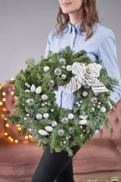 Noel havası. Kadın ellerinde taze ladin çelengi var. Xmas ağacı. Arka planda çelenk ışıkları Bokeh. — Stok fotoğraf