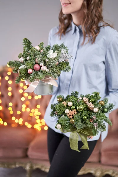 Twee kleine arrangementen van verse sparren in een metalen pot. Kerststemming. Bokeh van Garland lichten op de achtergrond. — Stockfoto