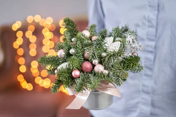 Humor de Natal. Pequeno acordo de abeto fresco em um pote de metal. Bokeh de luzes de guirlanda no fundo . — Fotografia de Stock