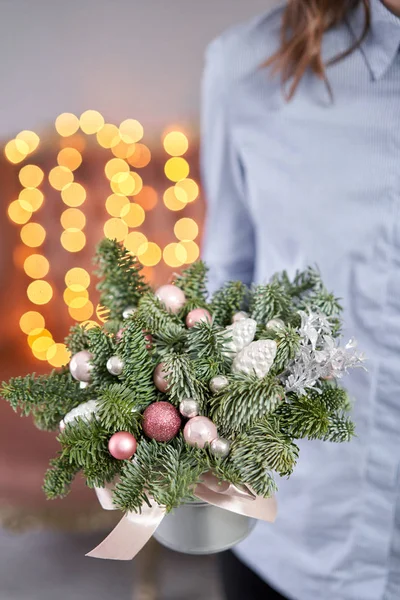 Kerststemming. Klein arrangement van verse sparren in een metalen pot. Bokeh van Garland lichten op de achtergrond. — Stockfoto