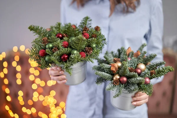 两个小排列新鲜云杉在一个金属罐。 圣诞气氛。 背景上加兰灯的Bokeh. — 图库照片