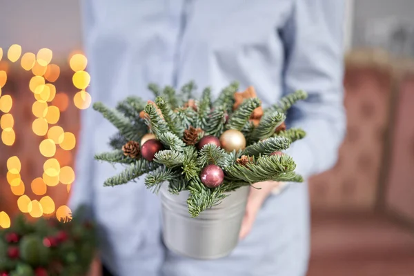 Humor de Natal. Pequeno acordo de abeto fresco em um pote de metal. Bokeh de luzes de guirlanda no fundo . — Fotografia de Stock