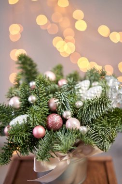 Metal bir tencerede iki küçük taze ladin aranjmanı. Noel havası. Arka planda çelenk ışıkları Bokeh.
