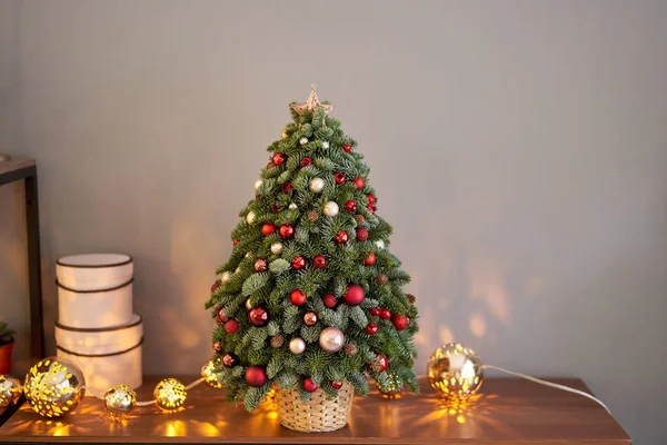 Bellissimo piccolo albero di Natale su tavolo di legno. Buon umore. Lampada a ghirlanda bokeh sullo sfondo. Carta da parati. Pino e abete danese, Nobilis — Foto Stock