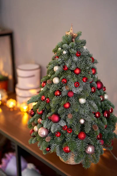 Beautiful small Christmas tree on wooden table. Happy mood. Garland lamp bokeh on background. Wallpaper. Danish pine and fir, Nobilis — Stock Photo, Image