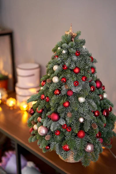 Bela árvore de Natal pequena na mesa de madeira. Bom humor. Lâmpada de guirlanda bokeh no fundo. Papel de parede. Pinheiro e abeto dinamarqueses, Nobilis — Fotografia de Stock