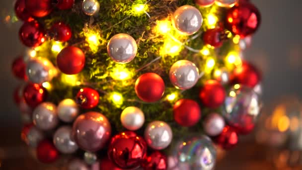 木製のテーブルの上に苔の美しい小さなクリスマスツリー。幸せな気分だ背景にガーランドランプボケ。アブストラクトブラー. — ストック動画