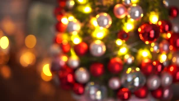 Gyönyörű kis moha karácsonyfa a fa asztalon. Boldog hangulatot. Garland lámpa bokeh a háttérben. Absztrakt homály. — Stock videók