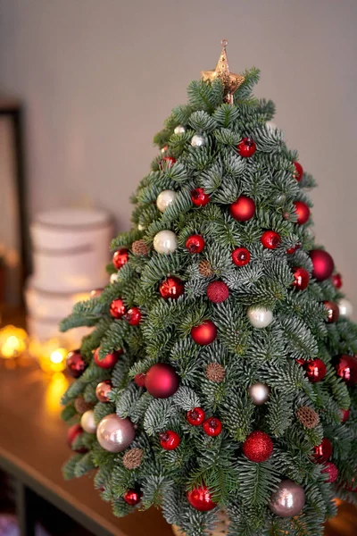 Bela árvore de Natal pequena na mesa de madeira. Bom humor. Lâmpada de guirlanda bokeh no fundo. Papel de parede. Pinheiro e abeto dinamarqueses, Nobilis — Fotografia de Stock