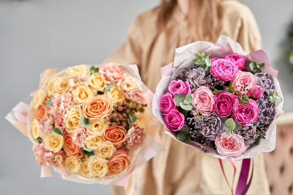 Loja floral europeia. Dois belos buquês de flores mistas em mãos de mulheres. o trabalho da florista em uma loja de flores. Entrega flor de corte fresco . — Fotografia de Stock