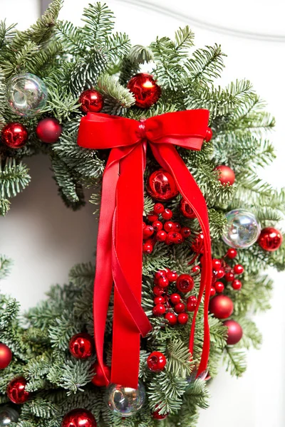 Linda grinalda de Natal vermelho de abeto fresco na porta branca. Entrada para a casa. Humor de Natal. Árvore natal . — Fotografia de Stock