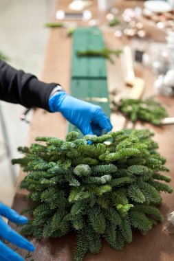 Bir kadın Noel düzenini süslüyor. Dekoratif süsler konusunda yüksek lisans. Noel dekorunu kendi elleriyle yaptılar. Yeni yıl kutlaması. Çiçekçi