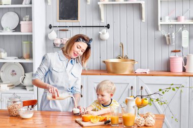 Anne ve oğul mutfakta bir kahvaltı yaparken gülümsüyorsun. Anne süt cam içine yağıyor