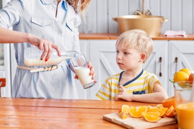 Anne ve oğul mutfakta bir kahvaltı yaparken gülümsüyorsun. Anne süt cam içine yağıyor