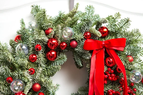 Schöner roter Weihnachtskranz aus frischer Fichte an der weißen Tür. Eingang zum Haus. Weihnachtsstimmung. Weihnachtsbaum. — Stockfoto