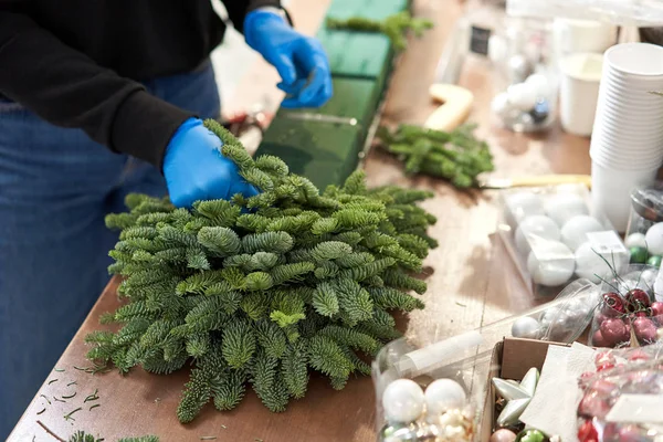 Uma mulher decora um arranjo de Natal. Master class em fazer ornamentos decorativos. Decoração de Natal com suas próprias mãos. A celebração do ano novo. Loja de flores — Fotografia de Stock