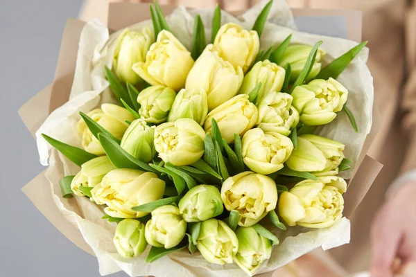 Jeune belle femme tenant dans sa main un bouquet printanier de tulipes jaunes. Bouquet de fleurs printanières fraîches coupées dans les mains des femmes — Photo