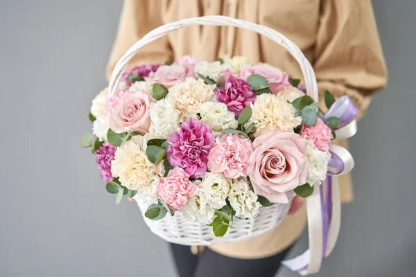 Flowers delivery. Flower arrangement in Wicker basket. Beautiful bouquet of mixed flowers in woman hand. Floral shop concept . Handsome fresh bouquet.