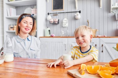 Anne ve oğul mutfakta bir kahvaltı yaparken gülümsüyorsun. Anne süt cam içine yağıyor