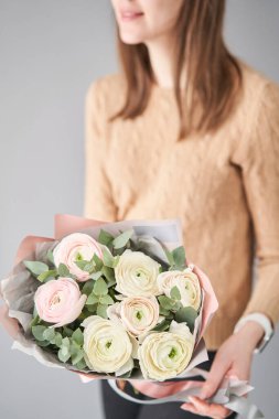 Kadınların elinde İranlı düğün çiçeği. Yeşil okaliptüslü soluk pembe ranunculus çiçekleri. Çiçekçi dükkanındaki çiçekçinin işi.
