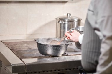 Şef Aşçı malzemeyi ekler. geleneksel et suyu ile sebze, kemik ve tarifi pişirme malzemeleri kapta. Bir tencereye karanlık taş zemin üzerine kepçe ile çorba. Üstten Görünüm