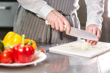 El bıçak kesim taze sebze ile closeup. Genç Şef kesme pancar beyaz kesme pano portre üzerinde. Bir restoran mutfağında yemek