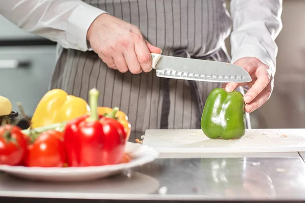 Крупный план руки с ножом, обрезающим свежий овощ. Молодой шеф-повар режет свеклу на белой доске крупным планом. Кулинария на кухне ресторана — стоковое фото