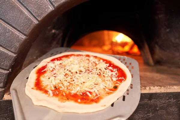 Billetta cruda per la cottura della gustosa pizza margherita nel forno tradizionale a legna nel ristorante napoletano. Pizza napoletana originale. Carbone caldo rosso . — Foto Stock