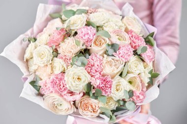 Kadınların elinde İranlı düğün çiçeği. Yeşil okaliptüslü soluk pembe ranunculus çiçekleri. Çiçekçi dükkanındaki çiçekçinin işi.