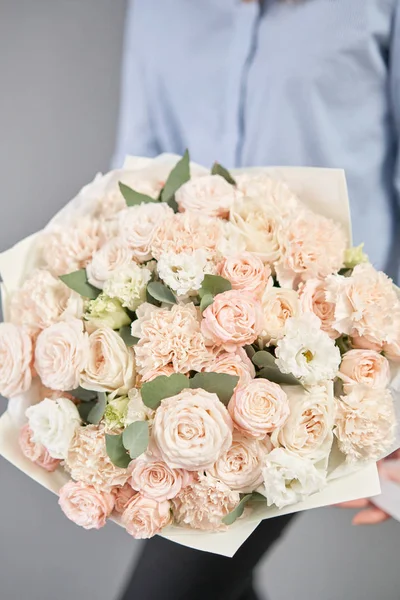 Bouquet mono de roses pulvérisées. Bouquet délicat de fleurs mélangées dans les mains des femmes. le travail du fleuriste dans un magasin de fleurs. Couleur pastel délicate. Fleurs fraîches coupées . — Photo