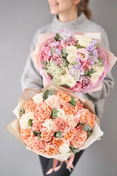 Due bellissimi mazzi di fiori misti nelle mani delle donne. il lavoro del fioraio in un negozio di fiori. Consegna fresco fiore reciso. Negozio floreale europeo . — Foto Stock