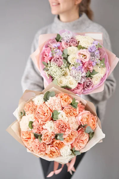 Twee prachtige boeketten van gemengde bloemen in de handen van vrouwen. het werk van de bloemist in een bloemenwinkel. Levering verse snijbloem. Europese bloemenwinkel. — Stockfoto