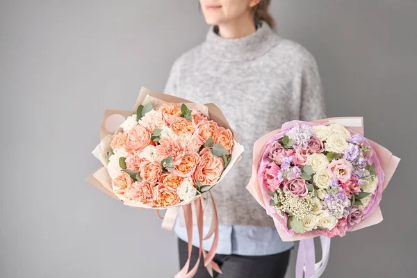 Dos hermosos ramos de flores mixtas en manos de mujeres. el trabajo de la floristería en una florería. Entrega flor cortada fresca. Tienda floral europea . — Foto de Stock