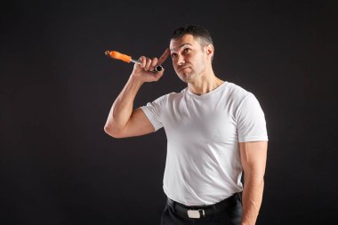 Siyah arka planda İngiliz anahtarı olan atletik bir adam. Beyaz tişört ve pantolon giyen tipik bir işçi değil. Başparmaklar yukarı.