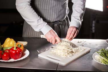 El bıçak kesim taze sebze ile closeup. Genç Şef kesme pancar beyaz kesme pano portre üzerinde. Bir restoran mutfağında yemek
