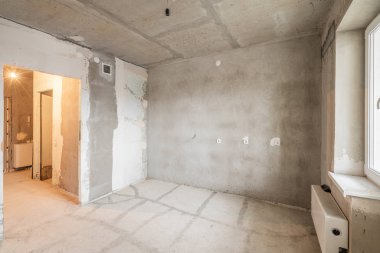 Tasarım için içi boş, gri beton duvar. Boş oda. Mesaj ve resim için boşluk. Beton duvarlar, döşemeler, yeni bir konut binasının içi. Yeni bir dairede bölümler.