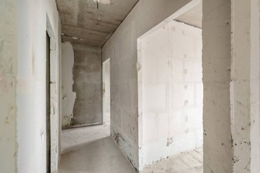 Tasarım için içi boş, gri beton duvar. Boş oda. Mesaj ve resim için boşluk. Beton duvarlar, döşemeler, yeni bir konut binasının içi. Yeni bir dairede bölümler.