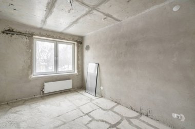 Tasarım için içi boş, gri beton duvar. Boş oda. Mesaj ve resim için boşluk. Beton duvarlar, döşemeler, yeni bir konut binasının içi. Yeni bir dairede bölümler.