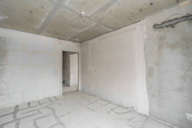 Tasarım için içi boş, gri beton duvar. Boş oda. Mesaj ve resim için boşluk. Beton duvarlar, döşemeler, yeni bir konut binasının içi. Yeni bir dairede bölümler.