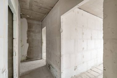 Tasarım için içi boş, gri beton duvar. Boş oda. Mesaj ve resim için boşluk. Beton duvarlar, döşemeler, yeni bir konut binasının içi. Yeni bir dairede bölümler.