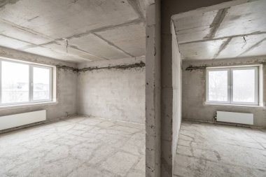 Tasarım için içi boş, gri beton duvar. Boş oda. Mesaj ve resim için boşluk. Beton duvarlar, döşemeler, yeni bir konut binasının içi. Yeni bir dairede bölümler.