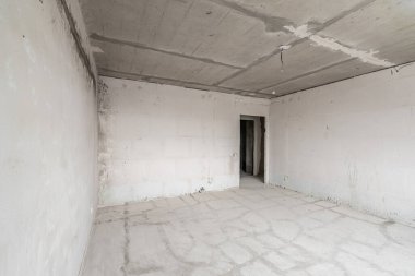 Tasarım için içi boş, gri beton duvar. Boş oda. Mesaj ve resim için boşluk. Beton duvarlar, döşemeler, yeni bir konut binasının içi. Yeni bir dairede bölümler.