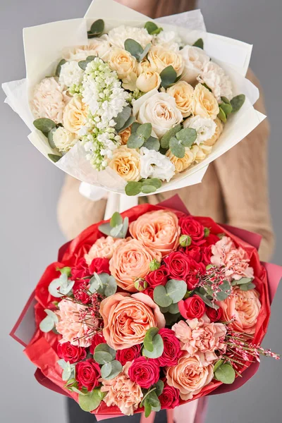 Två vackra buketter av blandade blommor i kvinnors händer. blomsterhandlarens arbete i en blomsteraffär. Leverera färsk snittblomma. Europeisk blomsteraffär. — Stockfoto