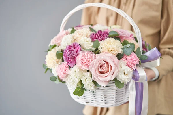 Flowers delivery. Flower arrangement in Wicker basket. Beautiful bouquet of mixed flowers in woman hand. Floral shop concept . Handsome fresh bouquet.