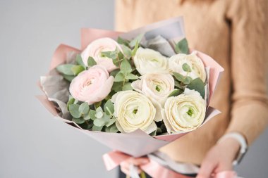 Kadınların elinde İranlı düğün çiçeği. Yeşil okaliptüslü soluk pembe ranunculus çiçekleri. Çiçekçi dükkanındaki çiçekçinin işi.