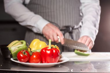 El bıçak kesim taze sebze ile closeup. Genç Şef kesme pancar beyaz kesme pano portre üzerinde. Bir restoran mutfağında yemek