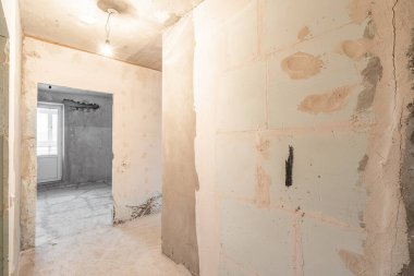 Tasarım için içi boş, gri beton duvar. Boş oda. Mesaj ve resim için boşluk. Beton duvarlar, döşemeler, yeni bir konut binasının içi. Yeni bir dairede bölümler.